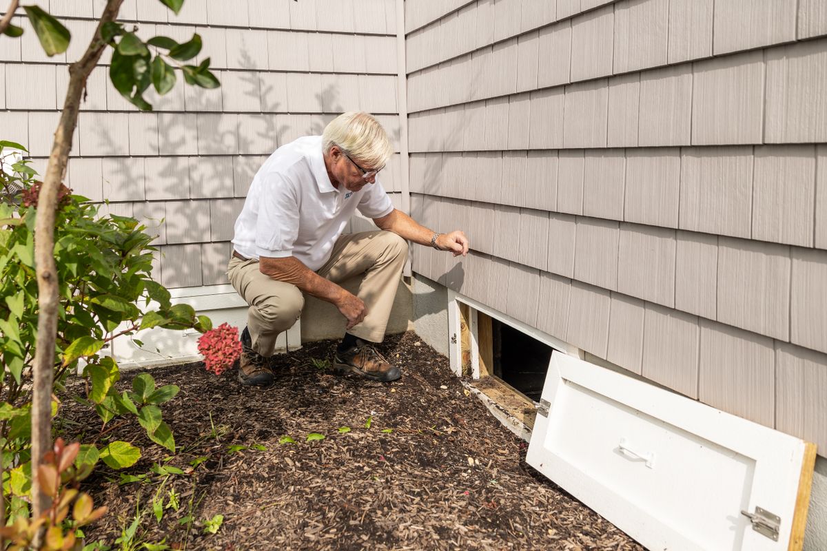 Inspector examining a crawl space access on a raised foundation home